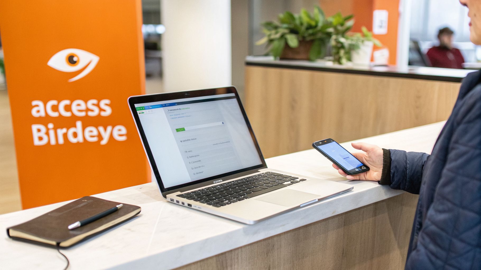 Person interacts with a laptop and smartphone on a counter, with an 'access Birdeye' sign.