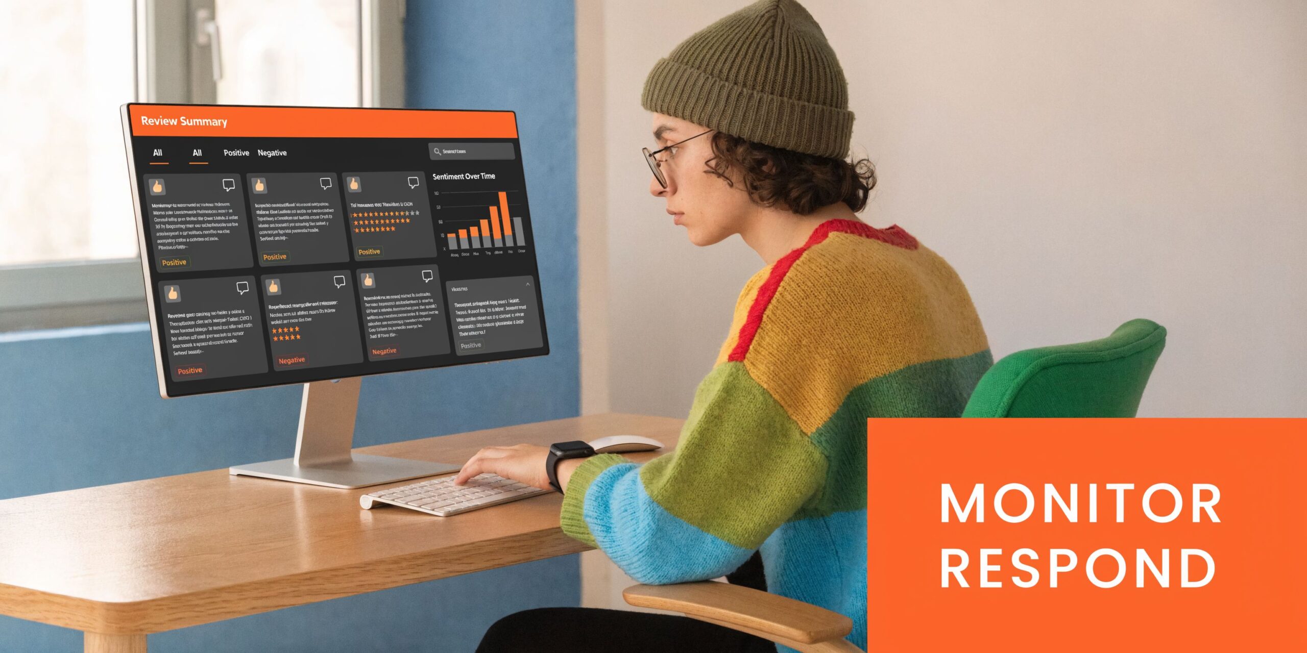 A young person with glasses and a beanie sitting at a desk monitoring digital customer reviews online.