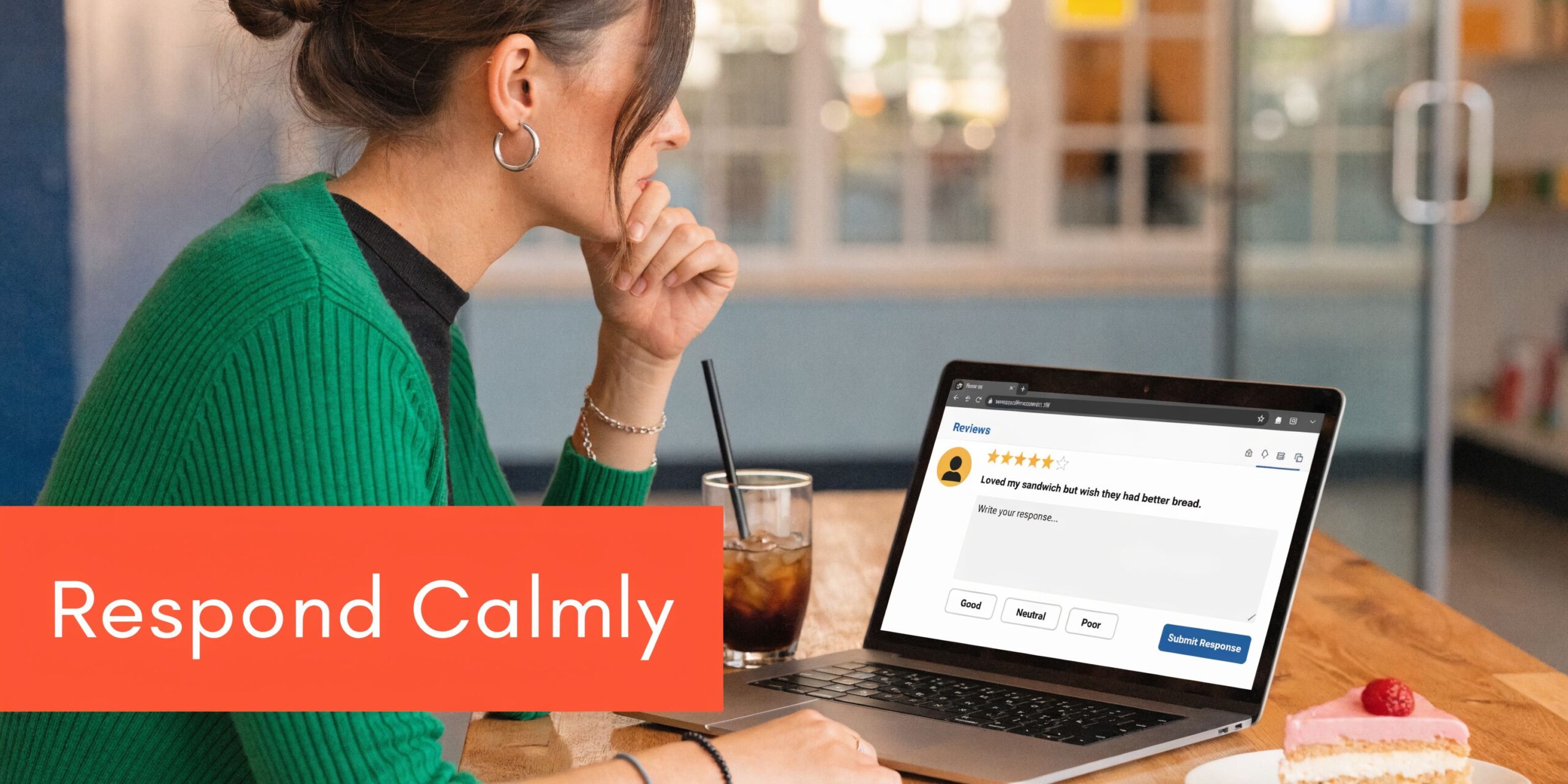 A woman in a green sweater thoughtfully types a response to a sandwich shop review on her laptop.