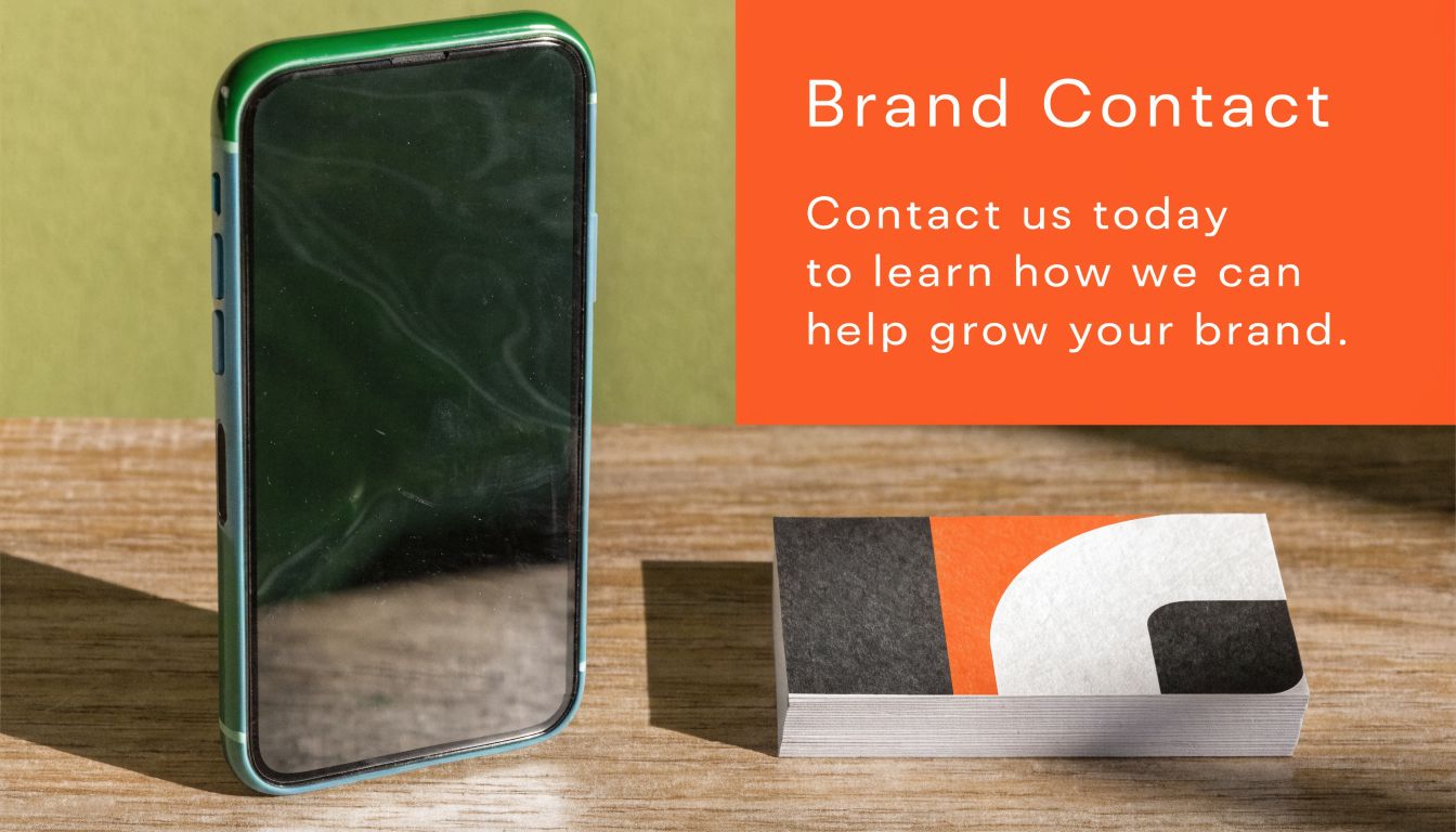 A smartphone stands next to a stack of business cards on a wooden desk surface.